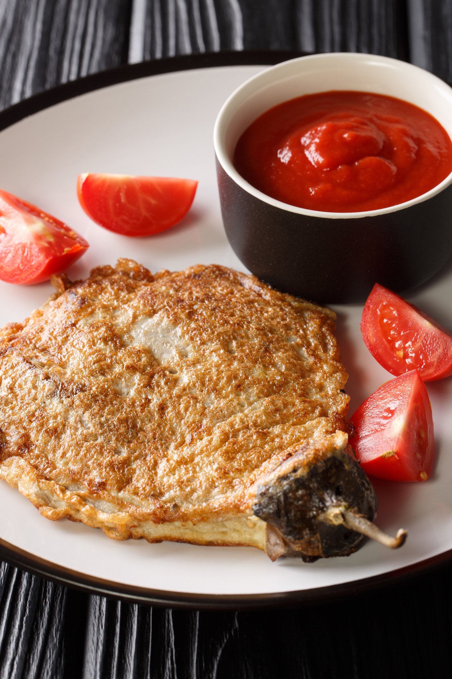 Tortang talong is a type of or eggplant omelet wherein grilled eggplants are soaked in a beaten egg mixture and then fried close-up in a plate. Vertical